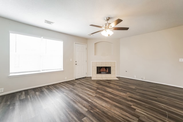 unfurnished living room featuring a tile fireplace, a textured ceiling, ceiling fan, and dark wood-type flooring