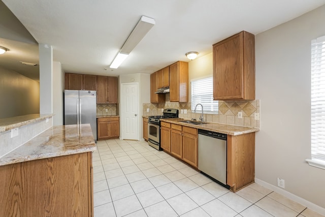 kitchen with decorative backsplash, light stone counters, sink, and appliances with stainless steel finishes