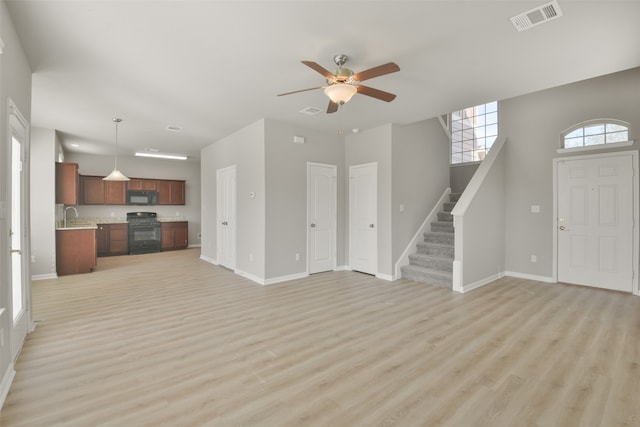 unfurnished living room with light wood-type flooring, ceiling fan, and sink