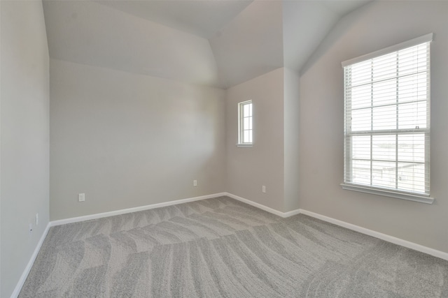 carpeted spare room with a healthy amount of sunlight and vaulted ceiling