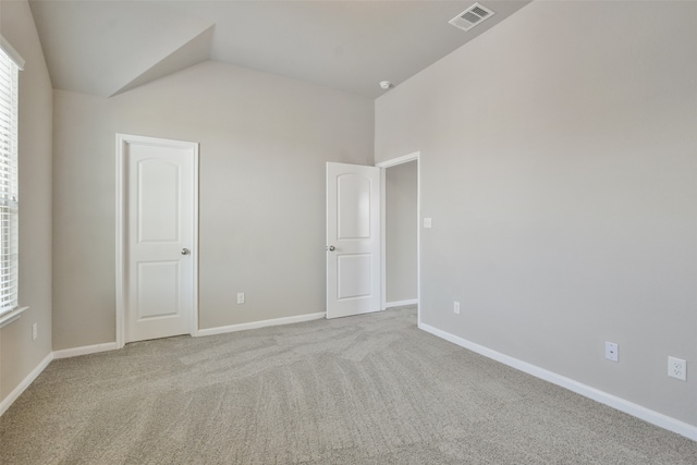 carpeted empty room featuring lofted ceiling