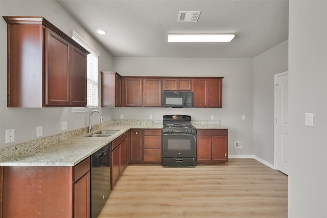 kitchen with light stone counters, sink, black appliances, and light hardwood / wood-style floors