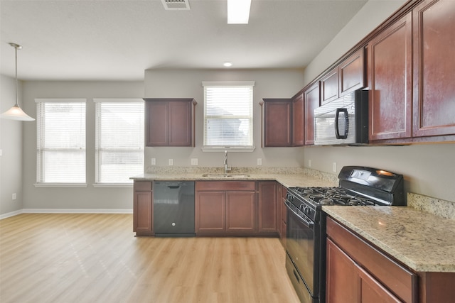 kitchen with black appliances, sink, light stone countertops, light wood-type flooring, and decorative light fixtures