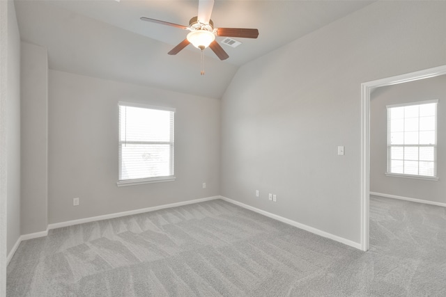 empty room featuring lofted ceiling, light colored carpet, and a healthy amount of sunlight