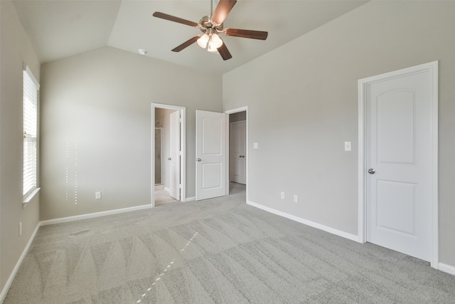 unfurnished bedroom featuring ensuite bath, light carpet, ceiling fan, and lofted ceiling