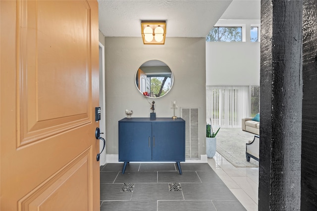 entrance foyer with a textured ceiling and dark tile patterned flooring