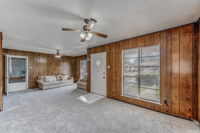 unfurnished living room with light colored carpet, ceiling fan, and wood walls