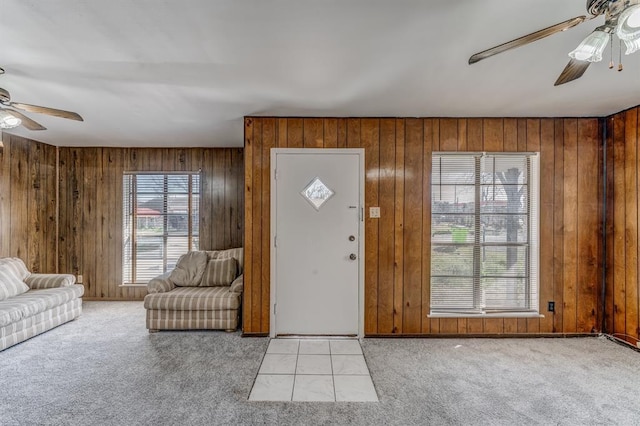 carpeted entrance foyer featuring ceiling fan and wood walls