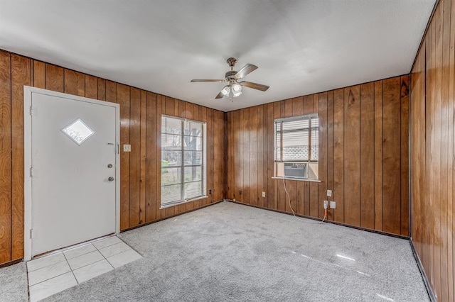 carpeted foyer with ceiling fan, cooling unit, and wood walls