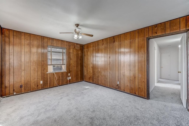 spare room featuring light carpet, cooling unit, ceiling fan, and wooden walls