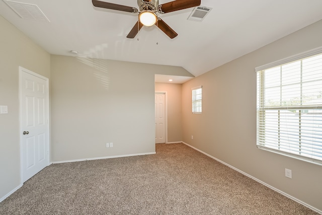 carpeted spare room featuring vaulted ceiling, ceiling fan, and a healthy amount of sunlight