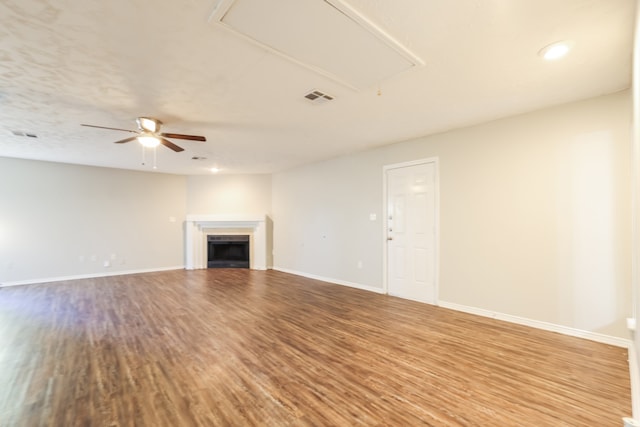 unfurnished living room featuring a tile fireplace, hardwood / wood-style floors, and ceiling fan