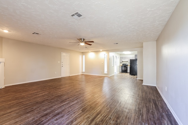 unfurnished living room with a textured ceiling, ceiling fan, and dark wood-type flooring