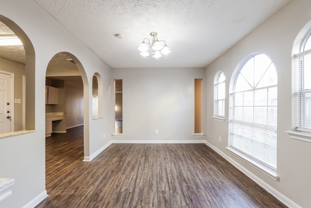 spare room with a notable chandelier, dark hardwood / wood-style flooring, and a textured ceiling