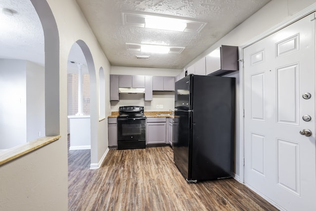 kitchen featuring dark wood-type flooring, black appliances, sink, gray cabinets, and a textured ceiling