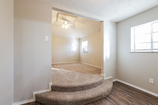 staircase featuring ceiling fan, a textured ceiling, and hardwood / wood-style flooring