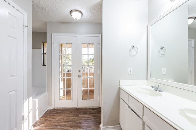 bathroom featuring french doors, vanity, wood-type flooring, and a textured ceiling