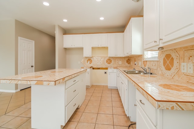 kitchen featuring a center island, white cabinets, sink, light tile patterned floors, and tasteful backsplash