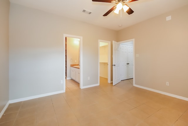 unfurnished bedroom featuring ensuite bathroom, a closet, ceiling fan, and light tile patterned floors