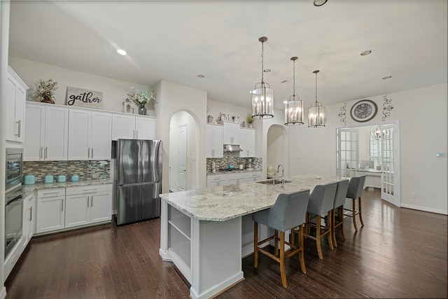 kitchen with white cabinets, an island with sink, stainless steel appliances, and dark hardwood / wood-style floors