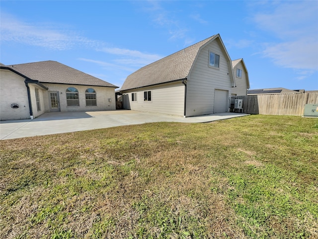 back of house featuring a garage, a patio area, and a lawn