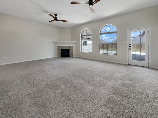 unfurnished living room featuring a tile fireplace, carpet, and ceiling fan