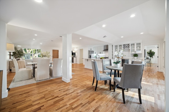 dining area featuring lofted ceiling, light wood-type flooring, and sink