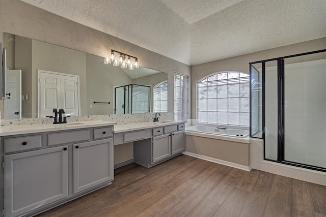 bathroom featuring hardwood / wood-style flooring, vanity, a textured ceiling, and plus walk in shower