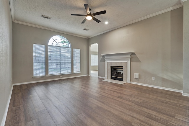 unfurnished living room featuring ceiling fan, crown molding, hardwood / wood-style floors, a textured ceiling, and a tiled fireplace