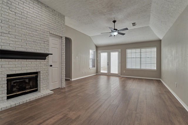 unfurnished living room with a textured ceiling, ceiling fan, dark wood-type flooring, and lofted ceiling