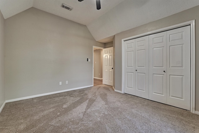 unfurnished bedroom featuring carpet flooring, a closet, vaulted ceiling, and ceiling fan