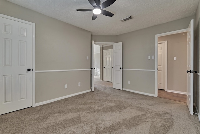 unfurnished bedroom with light carpet, a textured ceiling, and ceiling fan