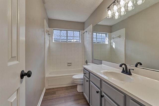 full bathroom with vanity, a textured ceiling, tiled shower / bath combo, wood-type flooring, and toilet