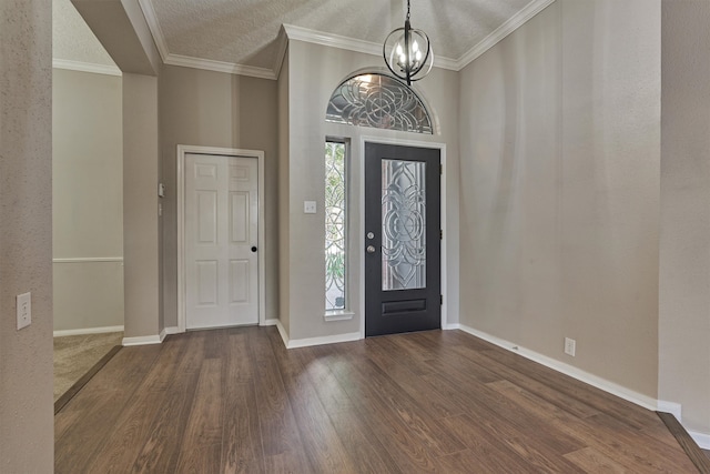 entryway with a textured ceiling, a chandelier, dark hardwood / wood-style floors, and ornamental molding