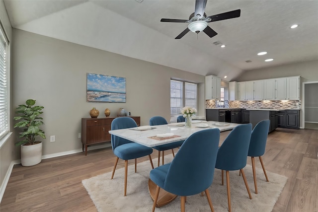 dining area with ceiling fan, light hardwood / wood-style flooring, vaulted ceiling, and sink