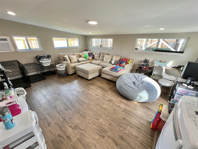 living room with wood-type flooring, vaulted ceiling, and a wall unit AC