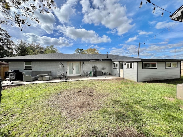 rear view of house with a yard, an outdoor living space, central AC, and a patio area