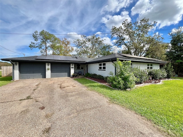 ranch-style house featuring a front yard, solar panels, and a garage