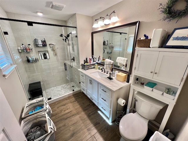 bathroom featuring toilet, vanity, a shower with shower door, and hardwood / wood-style flooring