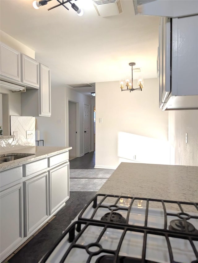 kitchen with white cabinetry, sink, tasteful backsplash, a notable chandelier, and pendant lighting