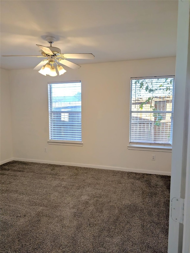 empty room with ceiling fan, a healthy amount of sunlight, and dark carpet