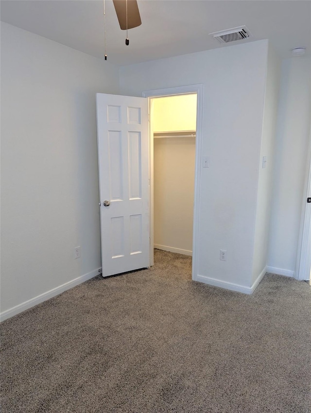 unfurnished bedroom featuring a walk in closet, ceiling fan, a closet, and carpet floors