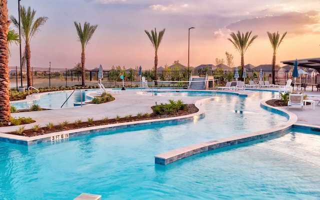 pool at dusk with fence and a community pool