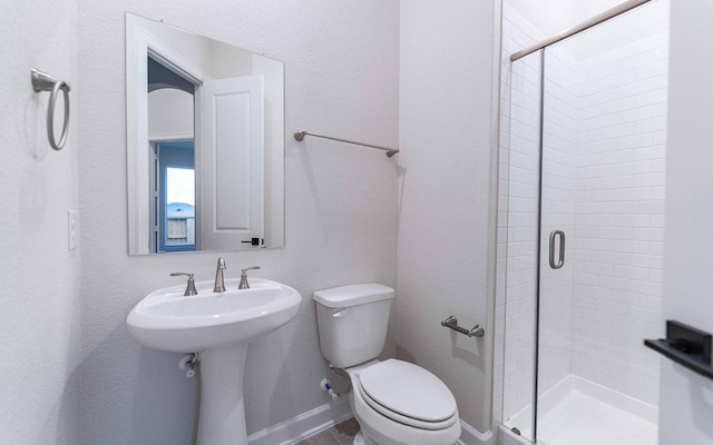 bathroom featuring a shower stall, toilet, and baseboards