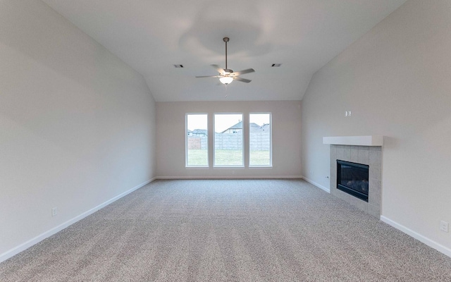 unfurnished living room with a tile fireplace, light colored carpet, lofted ceiling, and baseboards