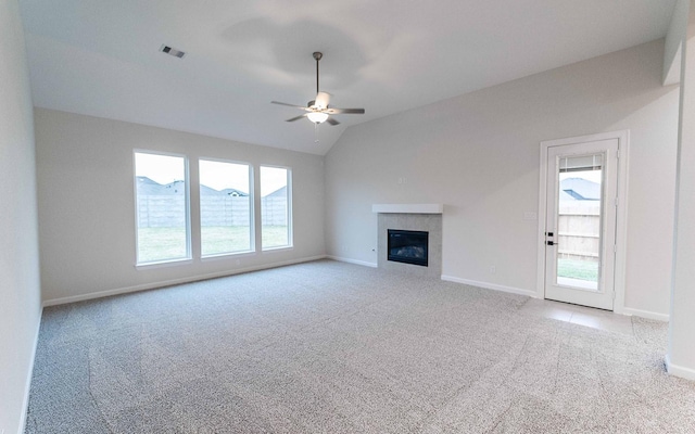 unfurnished living room with visible vents, a tiled fireplace, light carpet, vaulted ceiling, and ceiling fan