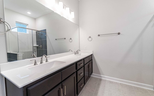 bathroom featuring baseboards, double vanity, a sink, and a shower stall