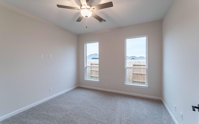 carpeted empty room with ceiling fan, visible vents, and baseboards