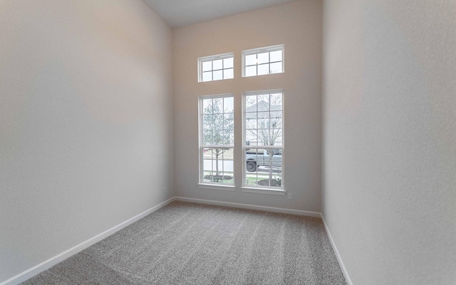 carpeted spare room featuring a healthy amount of sunlight and baseboards