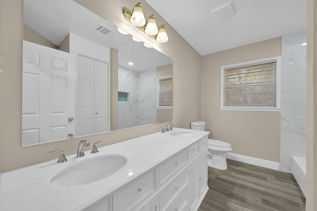 bathroom with vanity, toilet, wood-type flooring, and a tile shower